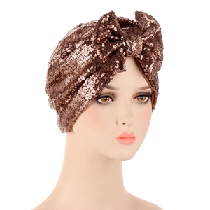 Detail of bronze sequined turban hat featuring a decorative knot bow on a mannequin