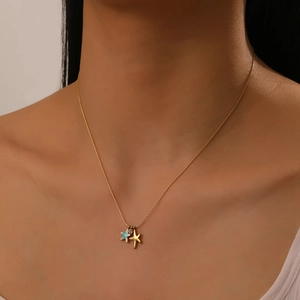 Detailed close-up of a gold necklace featuring blue enamel and gold starfish pendants with diamond