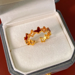 Detailed macro of golden butterfly open ring with red enamel and beaded metal edges