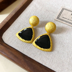 Detail of vintage geometric earrings with gold hammered texture and black enamel finish