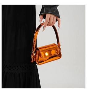 Macro shot of vibrant glossy orange patent leather bag with metallic mirror finish detail