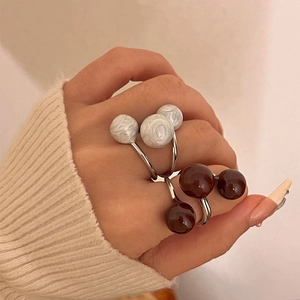 Three-layer open ring set with marble white and reddish-brown spheres on model hand