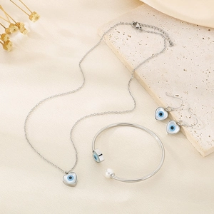 Detailed view of silver jewelry set with evil eye heart pendants and pearl accents