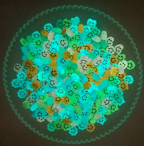 Perline acriliche luminose con faccina sorridente che brillano al buio in una ciotola