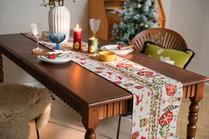 Detail of Christmas table runner featuring red reindeer, green trees, and woven texture