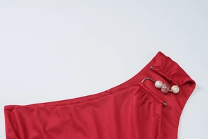 Dettaglio macro del crop top rosso con anello in metallo e perle decorative marmorizzate
