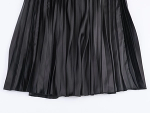 Close-up of black pleated skirt hem showing smooth satin fabric texture and sharp folds