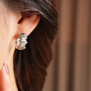 Close-up of silver irregular textured hoop earring on model with molten lava metal finish