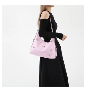 Detail view of pink shoulder bag with silver butterfly accents worn by a model