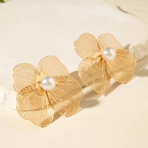 Détail de boucles d'oreilles fleur dorée avec pétales en fil et perles élégantes