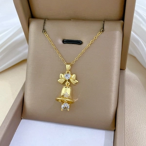 Detailed shot of a gold bow and bell pendant necklace with sparkling zircons in a gift box