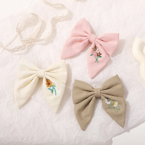Détail de broderie florale sur barrettes à nœuds en coton et lin aux tons doux