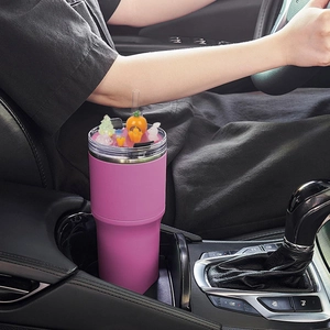 Pink 40oz tumbler in car cup holder with cute cartoon character lid decorations
