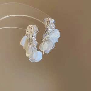 Détail de boucles d'oreilles branche en argent avec disques de nacre blanche suspendus