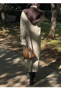 Beige hooded long coat with soft texture and sleeve straps shown in autumn park setting