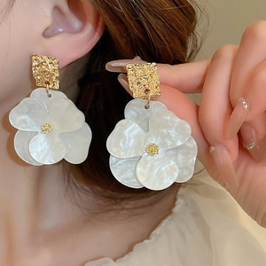 Macro detail of French retro flower earrings with pearl finish and golden tassels
