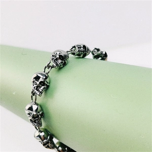 Close-up of silver punk style skull link bracelet on a light green display cone