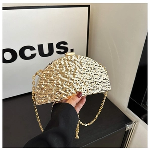 Detail of a golden semicircular clutch with hammered metal texture and gold chain strap