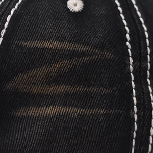 Detail of washed black denim baseball cap with contrast stitching and embroidery