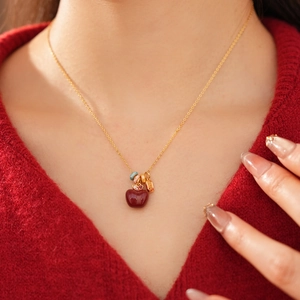 Primo piano della collana placcata oro 18k con ciondolo a mela rossa su modella