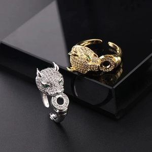 Detail of leopard head rings in gold and silver finish with green stone eyes and zircon stones