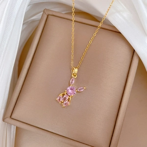 Macro detail of pink zircon bunny pendant on a golden chain inside a luxury jewelry box