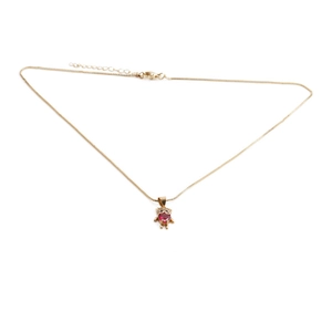 Détail du pendentif ours doré avec gemme cœur rouge sur un collier à chaîne fine dorée