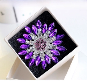 Detail of flower brooch with purple marquise rhinestones in a white gift box