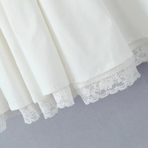 Detailed close-up of white dress hem featuring delicate lace edges and premium fabric texture