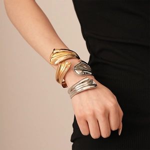 Detailed view of layered wavy metallic cuff bracelets in polished gold and silver finish