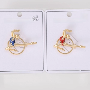 Detailed view of red and blue enamel gymnastic girl brooches on a white display card