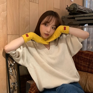Yellow knitted gloves featuring a red bow pattern shown on hands in a studio setting