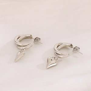 Close-up of silver double-hoop earrings with 3D heart charms on pink satin fabric