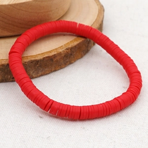 Detail van een rode Boheemse Heishi-kralenarmband op een rustieke houten standaard