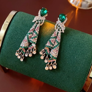 Close-up of vintage emerald water-drop earrings with colorful crystal tassels on velvet