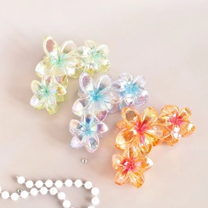 Close-up of three gradient floral hair claws in pearlescent yellow, purple, and orange
