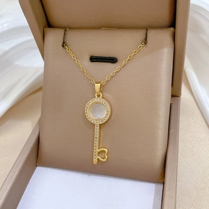 Close-up of golden key necklace with cat eye stone and hollow heart pendant