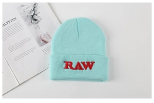 Detail of mint green knitted beanie with red RAW embroidery on the folded cuff