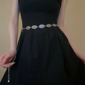 Close-up of silver metal waist chain with oval carved links on a black dress
