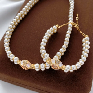 Détails de l'ensemble collier et bracelet en perles plaqué or sur un présentoir en velours
