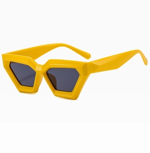 Detail view of bold yellow cat-eye sunglasses featuring a thick geometric frame design