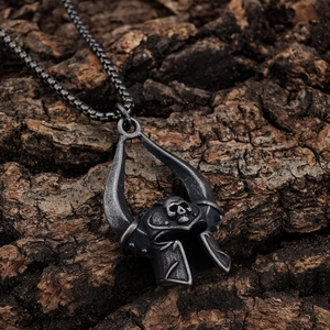 Gothic skull mask pendant in vintage steel on a textured bark background with a chain