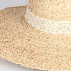 Close-up of natural raffia weave texture and white lace ribbon on a summer sun hat