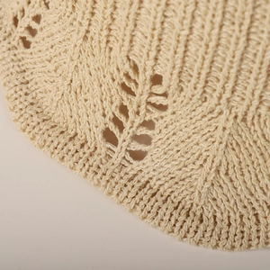 Macro shot of beige crochet straw hat showing delicate leaf-shaped hollow lace details