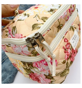 Detailed close-up of quilted floral makeup bag with metal zippers and cotton drawstring