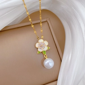 Détail du pendentif fleur dorée avec cœur en zircon et perle suspendue élégante