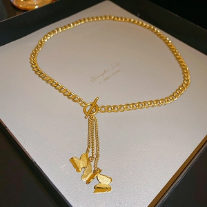 Macro di una collana in acciaio inossidabile dorato con ciondoli a farfalla testurizzati