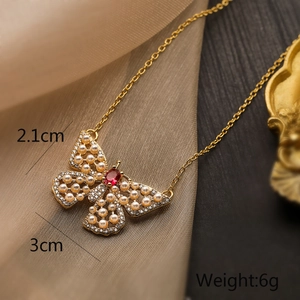 Macro detail of butterfly pendant with red gemstone, pearls and crystals on silk