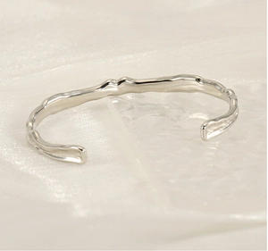 Dettaglio macro del bracciale a polsino in acciaio al titanio con texture martellata argento
