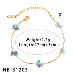 Détail du bracelet en acier doré avec des breloques fleurs en perles bleues et blanches